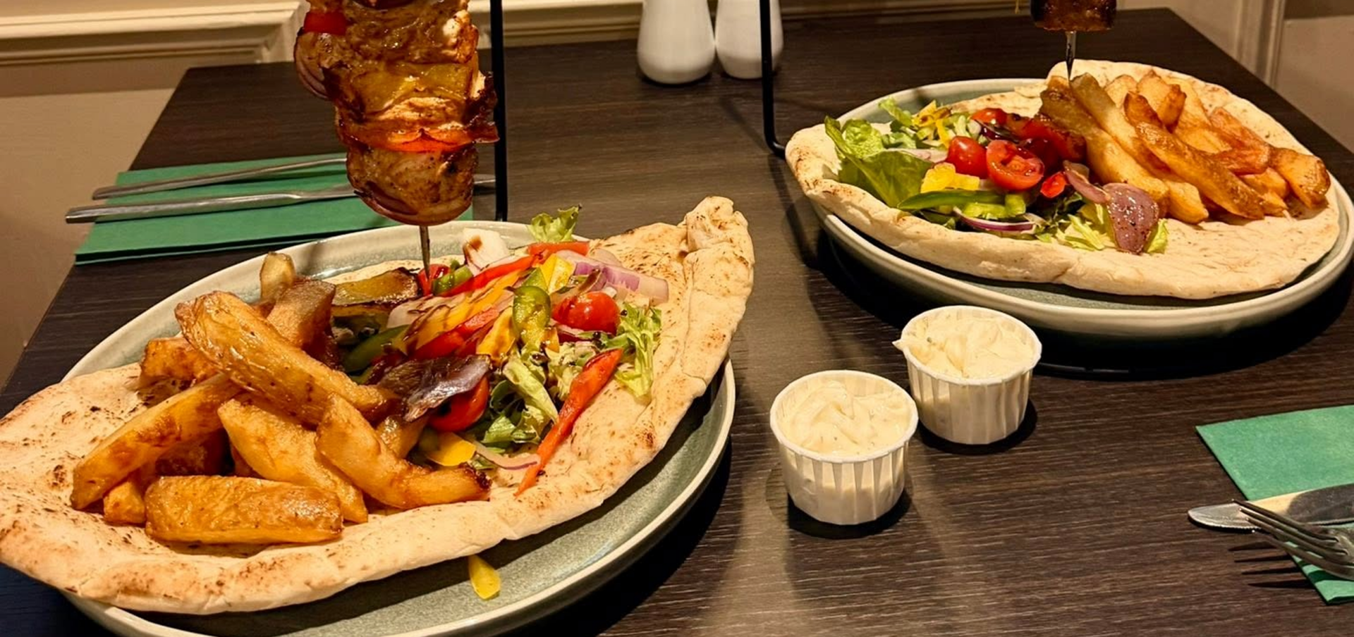 Two kebab dishes with salad and fries